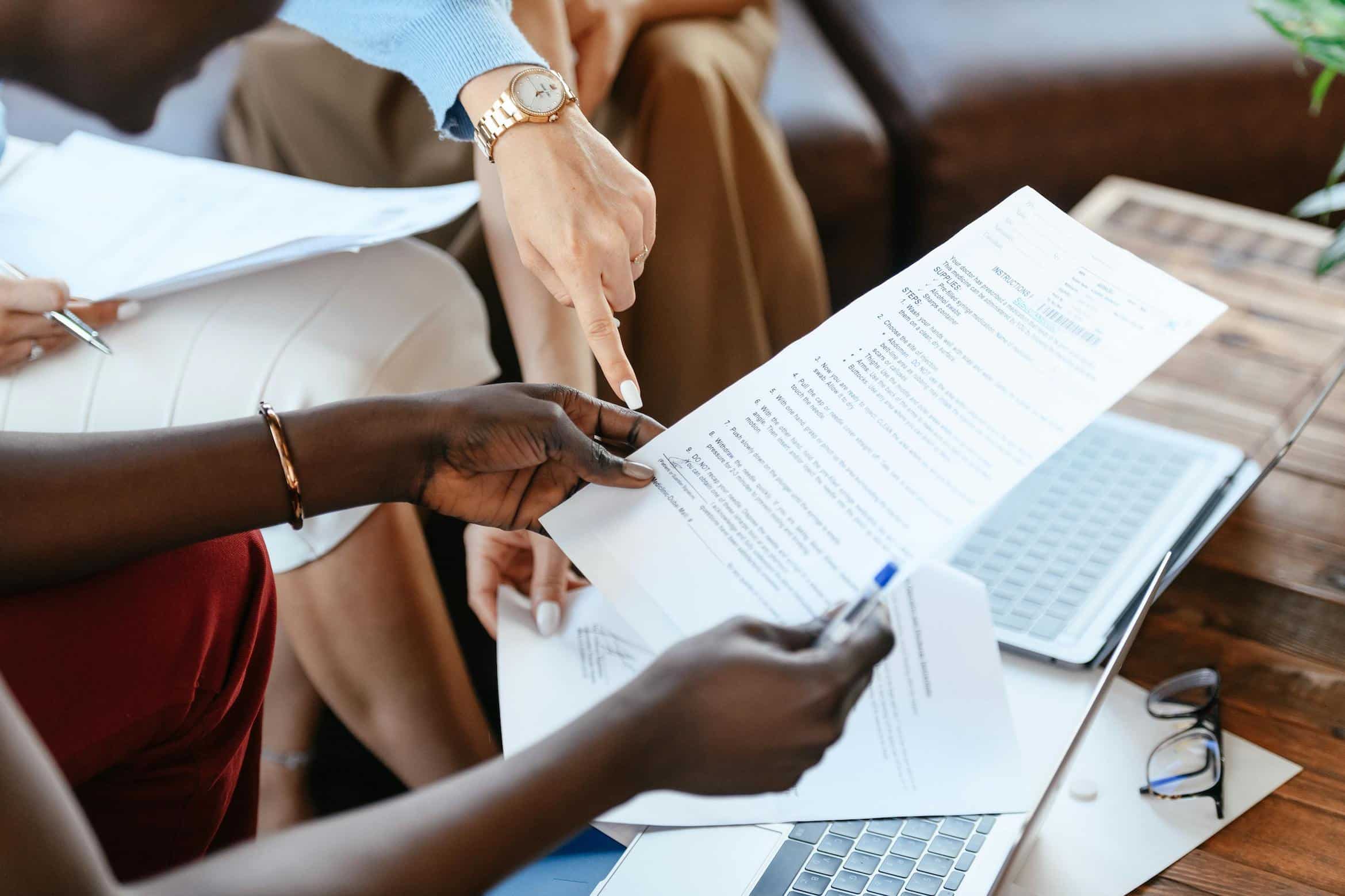 Multiethnic businesswomen checking information in documents, symbolizing tenants reviewing rental contracts and understanding key lease terms.