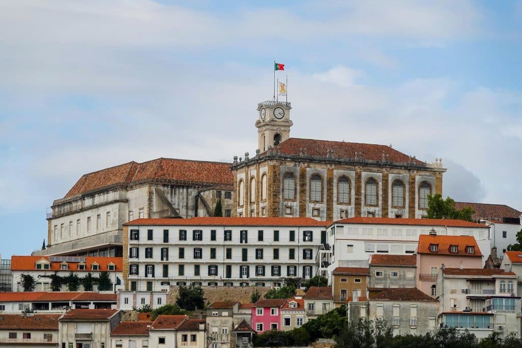 Historical building in Coimbra District, Portugal, with a waving Portuguese flag, reflecting the city’s rich heritage and cultural pride.