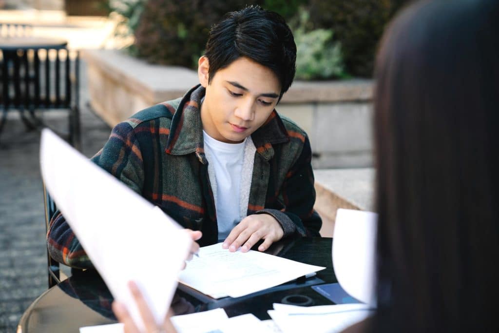 A man in a white inner shirt reading papers, symbolizing a tenant reviewing hidden rental costs and lease agreements.