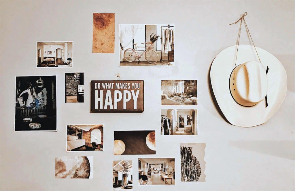 A gallery wall with photos, art, and an inspirational sign, featuring a cowboy hat, showcasing budget-friendly DIY wall decor for renters.