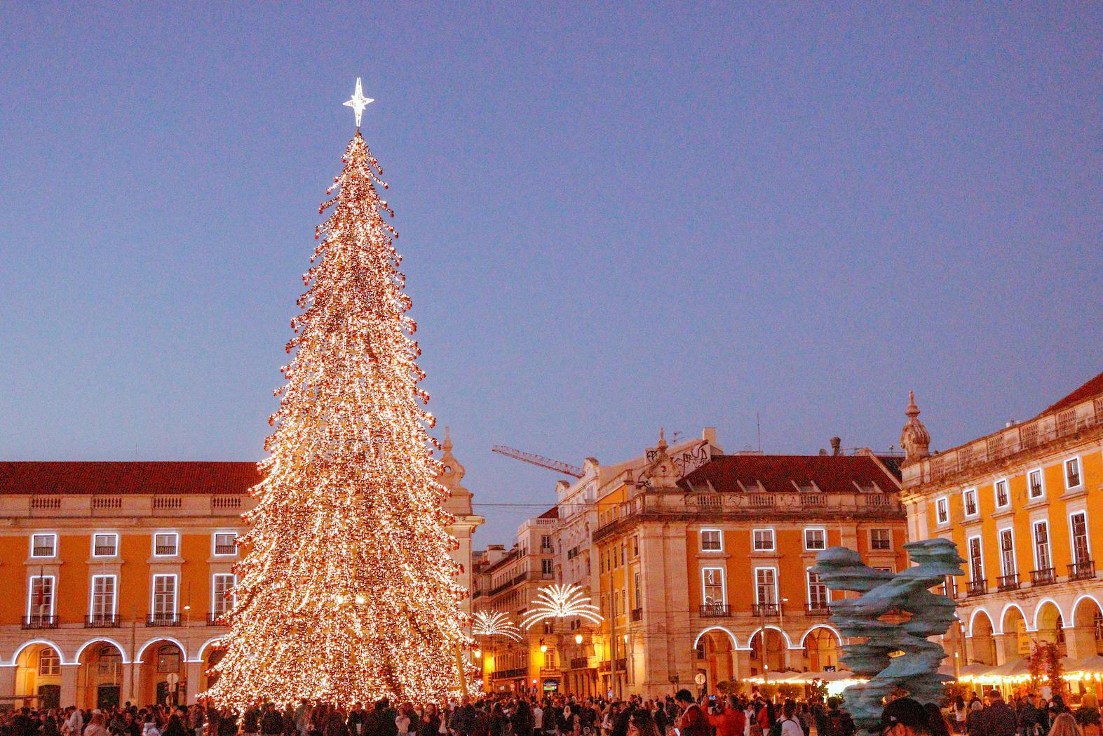 Visitors enjoying a festive Christmas market in Lisbon with twinkling lights and holiday decorations.