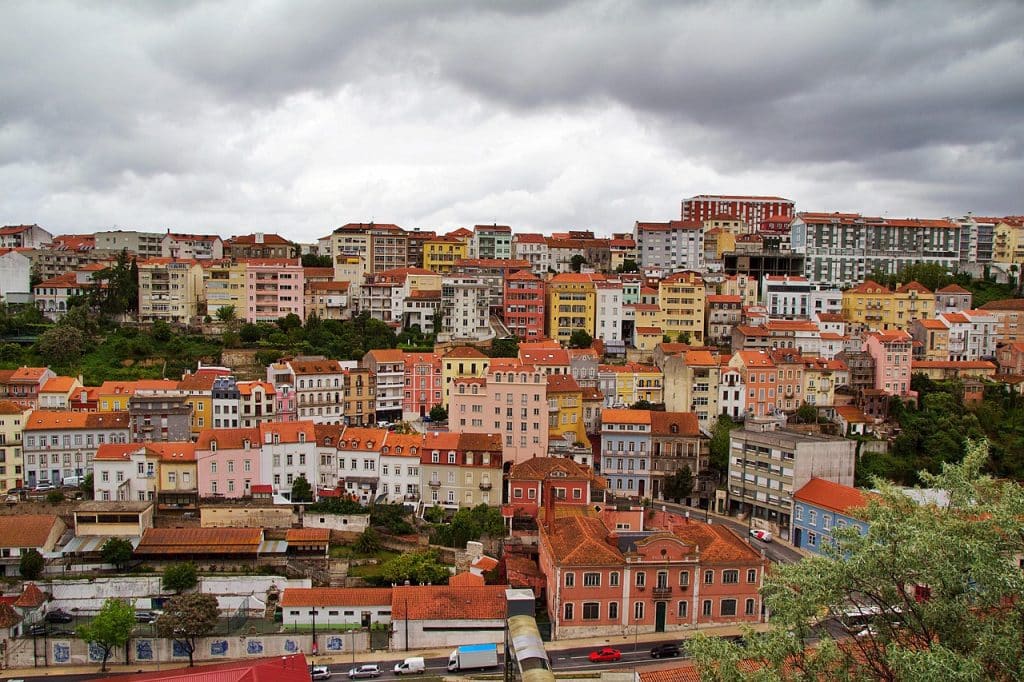 Charming residential street with colorful buildings and local shops in Coimbra’s Baixa neighborhood, highlighting living costs and cultural vibrancy.