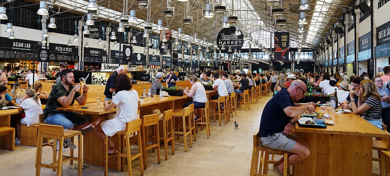 Crowds dining and enjoying drinks at the Time Out Market in Lisbon, Portugal, reflecting a vibrant culinary atmosphere similar to food and wine festivals.