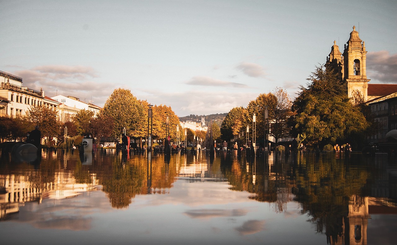 Stunning view of Braga, Portugal, with a serene lake reflecting the city’s buildings and cathedral at sunset, capturing the blend of urban life and natural beauty.