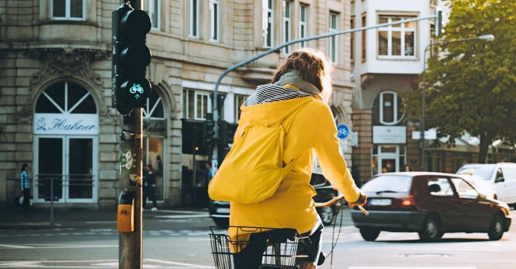 Cyclist in a yellow jacket riding through the urban streets of Frankfurt, Germany, showcasing local bicycle safety and infrastructure.