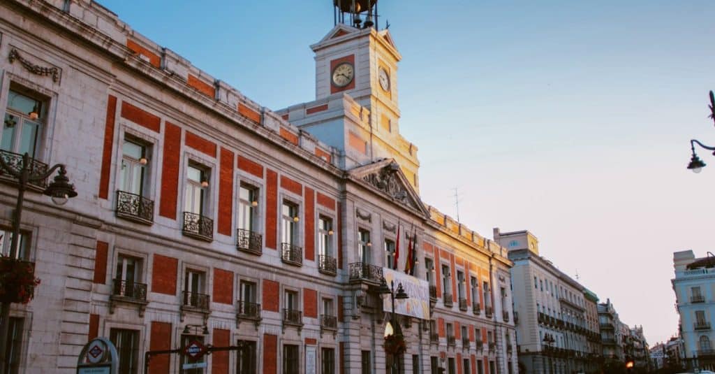 View of the iconic Puerta del Sol clock tower in Madrid, Spain, during dusk, showcasing the historic and cultural significance of this central landmark.