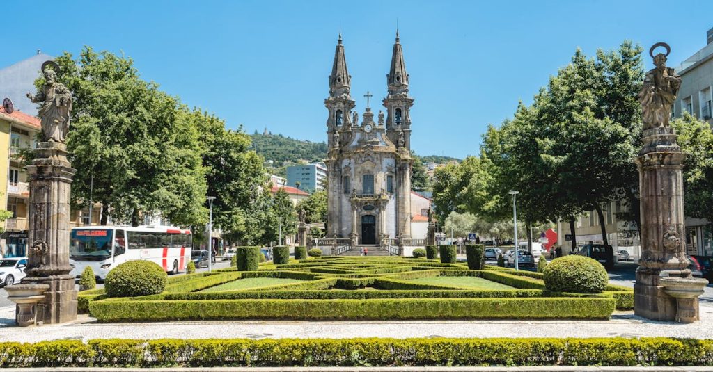 Sunlit view of Nossa Senhora da Consolação Church in Guimarães, Portugal, surrounded by lush gardens, showcasing the city's historic charm and cultural heritage.