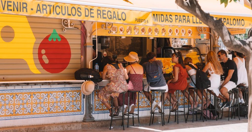 People enjoying a meal at a street food stall in sunny Valencia, Spain, highlighting the city's vibrant food culture and social dining experience.