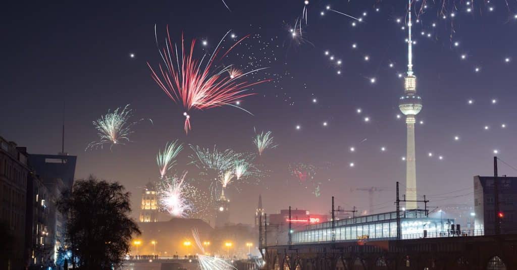Captivating fireworks light up the Berlin night sky above the iconic TV Tower, reflecting beautifully in the river, celebrating New Year's Eve in Germany’s capital.