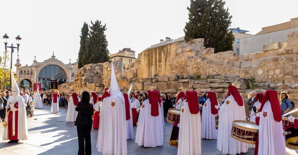 Majestic Holy Week procession in Zaragoza with people wearing white capirotes, showcasing the deep cultural and religious traditions of Spain.