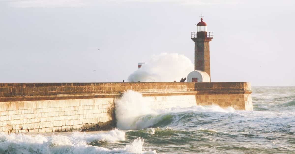 Scenic view of crashing waves against the Douro River lighthouse in Porto, Portugal, showcasing the dramatic coastal beauty of Foz do Douro.