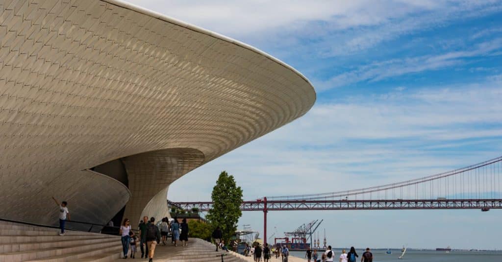 A scenic walkway with modern architecture in Lisbon, Portugal, featuring a clear blue sky backdrop.