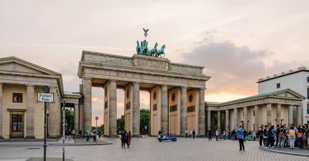 Scenic view of Berlin’s Brandenburg Gate with people gathering at sunset, symbolizing the expat experience and cost of living in the city.