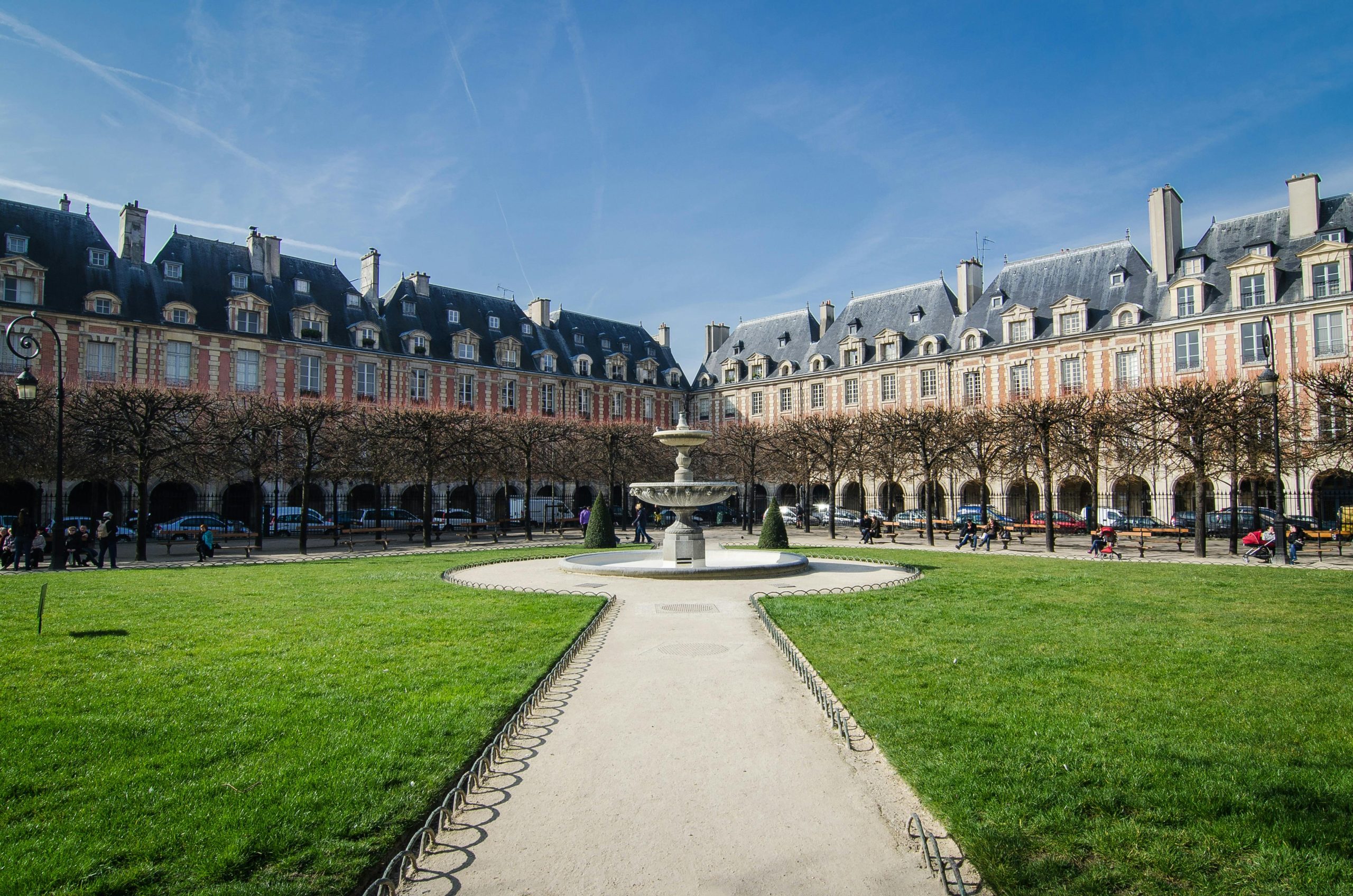 The elegant Place des Vosges in Le Marais, Paris, showcasing its historic red-brick arcades, lush gardens, and medieval charm.