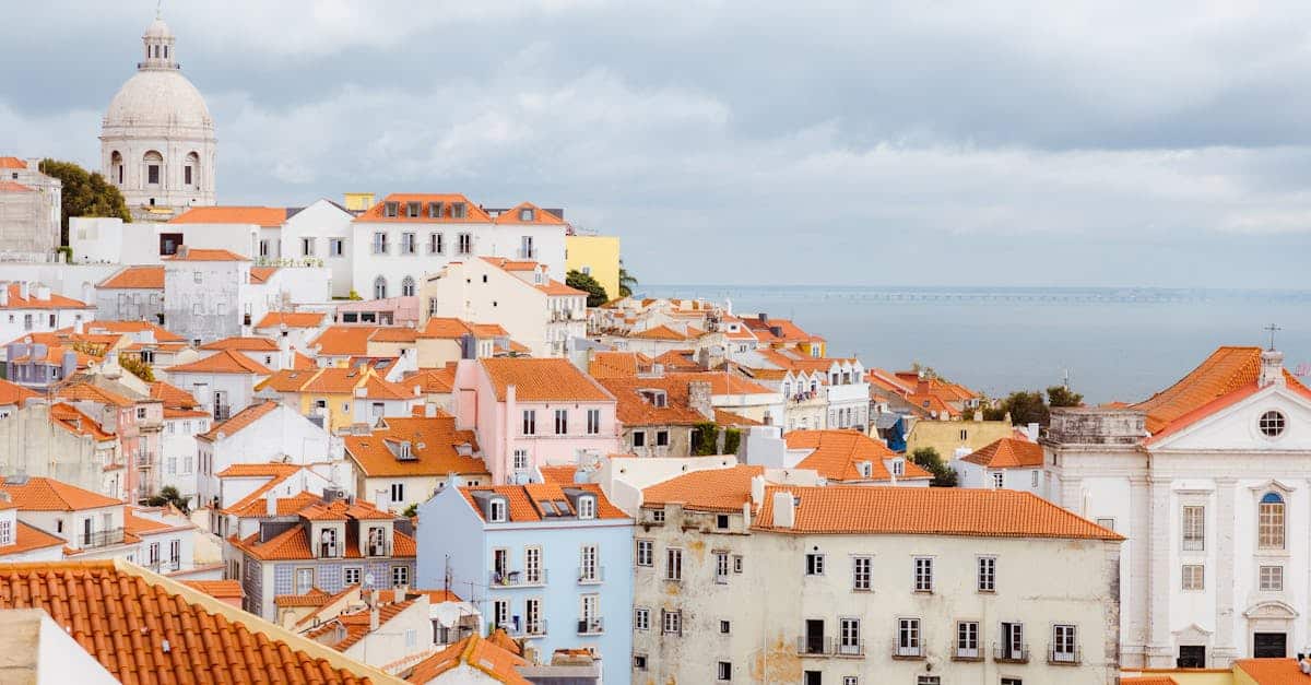 High-angle view of Alfama’s aged tiled rooftops with the Tagus River in the background, showcasing the scenic beauty of Lisbon’s oldest neighborhood.