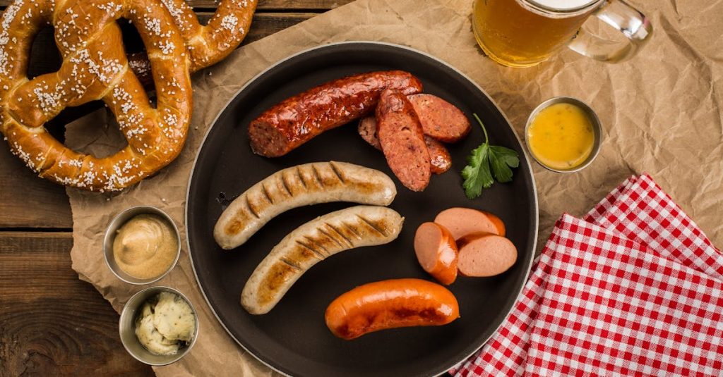 A top view of a traditional German meal featuring sausages, pretzels, dips, and beer on a rustic table, showcasing Germany’s rich food culture.