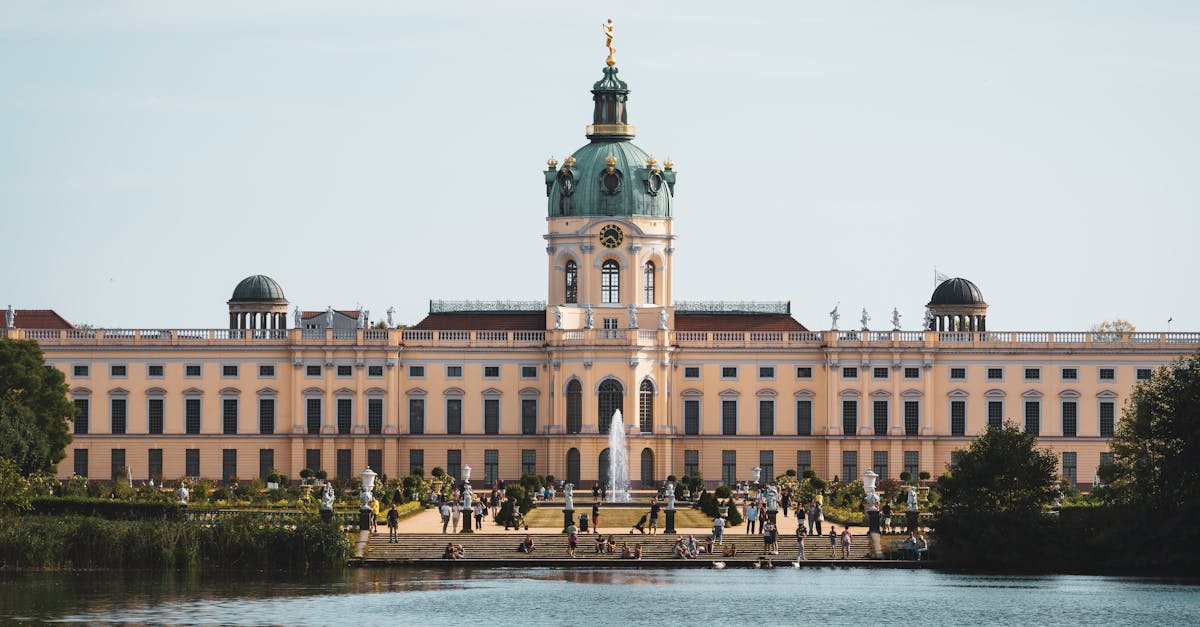 Stunning view of Charlottenburg Palace with a serene lake and a vibrant summer scene in Berlin, Germany, showcasing the district’s historical and luxurious charm.