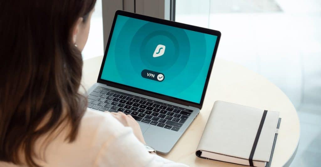 A woman working on a laptop with a VPN icon on the screen, ensuring secure online browsing and protection against scams in Germany.