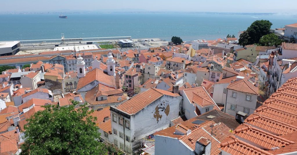 High-angle view of aged tiled roofs of houses along the Lisbon shoreline, showcasing the charm of neighborhoods popular among students.