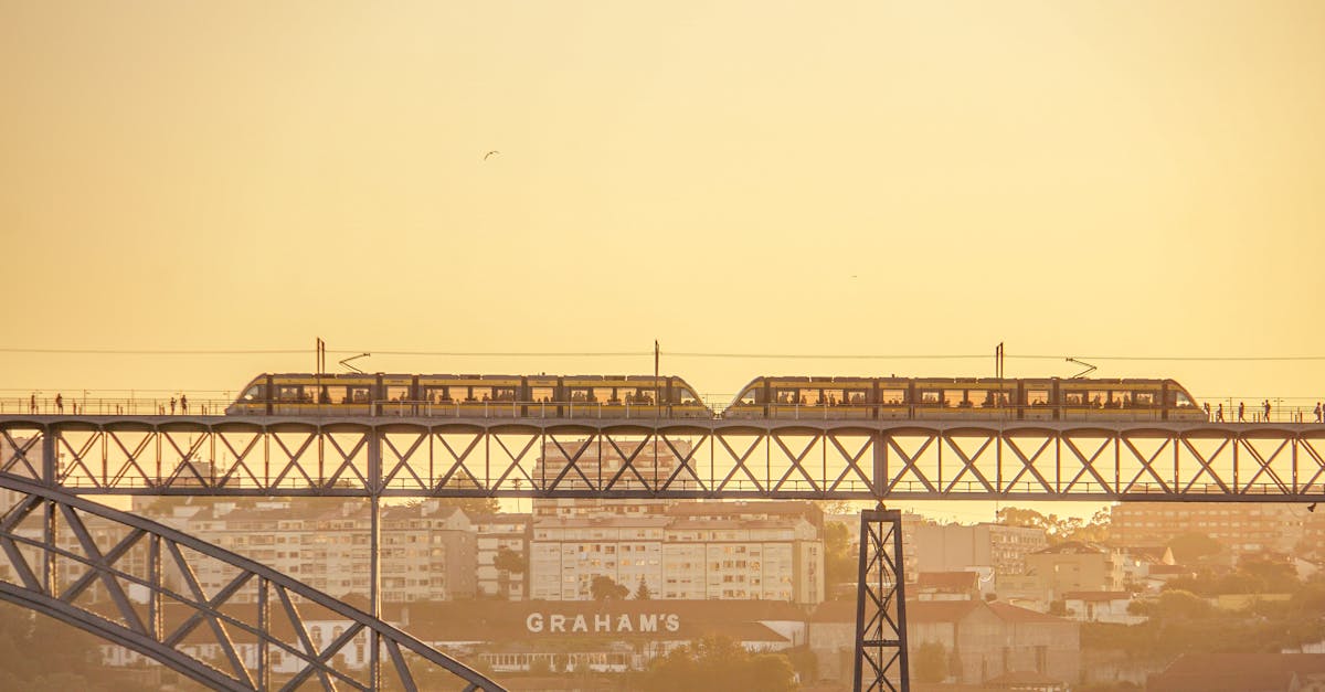 Train crossing the Dom Luís I Bridge at sunset in Porto, Portugal, showcasing the city's architecture and scenic river views.