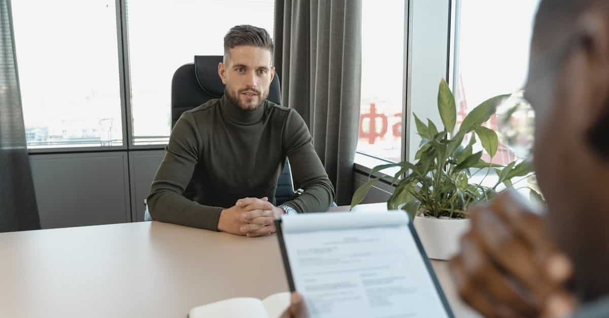 A professional man in a turtleneck at an office desk during an interview, representing job opportunities and the hiring process for expats in Berlin.