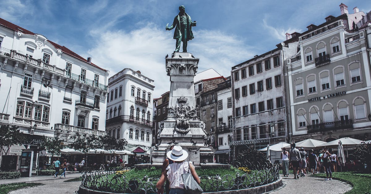 Monumental statue in a bustling square in Coimbra, Portugal, capturing local life, vibrant community interactions, and the city’s historic architecture.