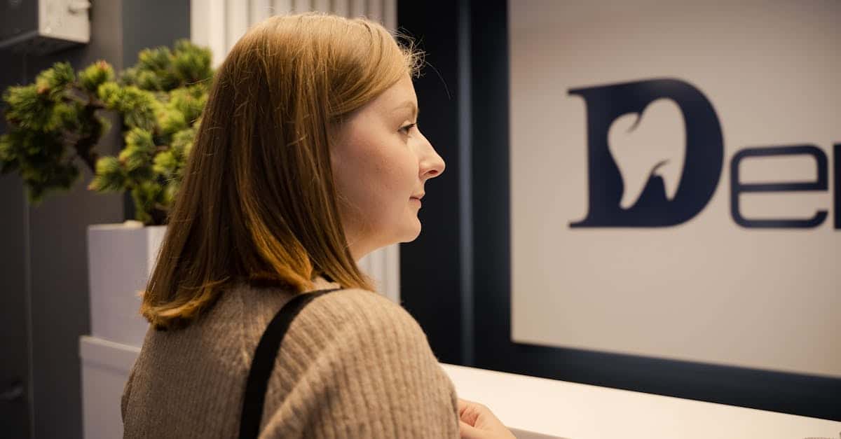 A woman waiting at the dental clinic reception, viewed from the side in an indoor setting, symbolizing healthcare access and health insurance for expats in Berlin.