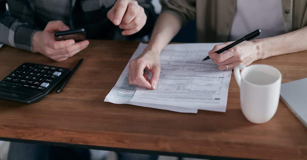 A couple managing their finances at home with a calculator, smartphone, and documents, organizing their financial planning for living in Spain.