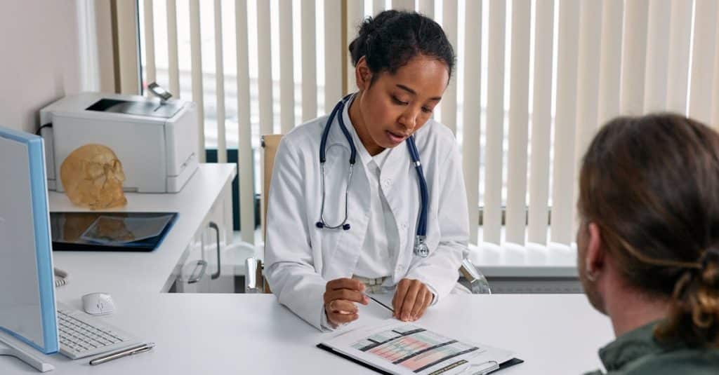 A doctor consulting with a patient in Spain, discussing a medical chart in a healthcare office.