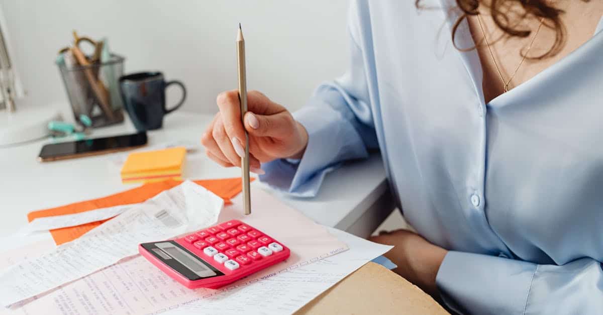 An expat woman calculating expenses with a calculator and papers at her desk, managing her finances and tax obligations in Spain.