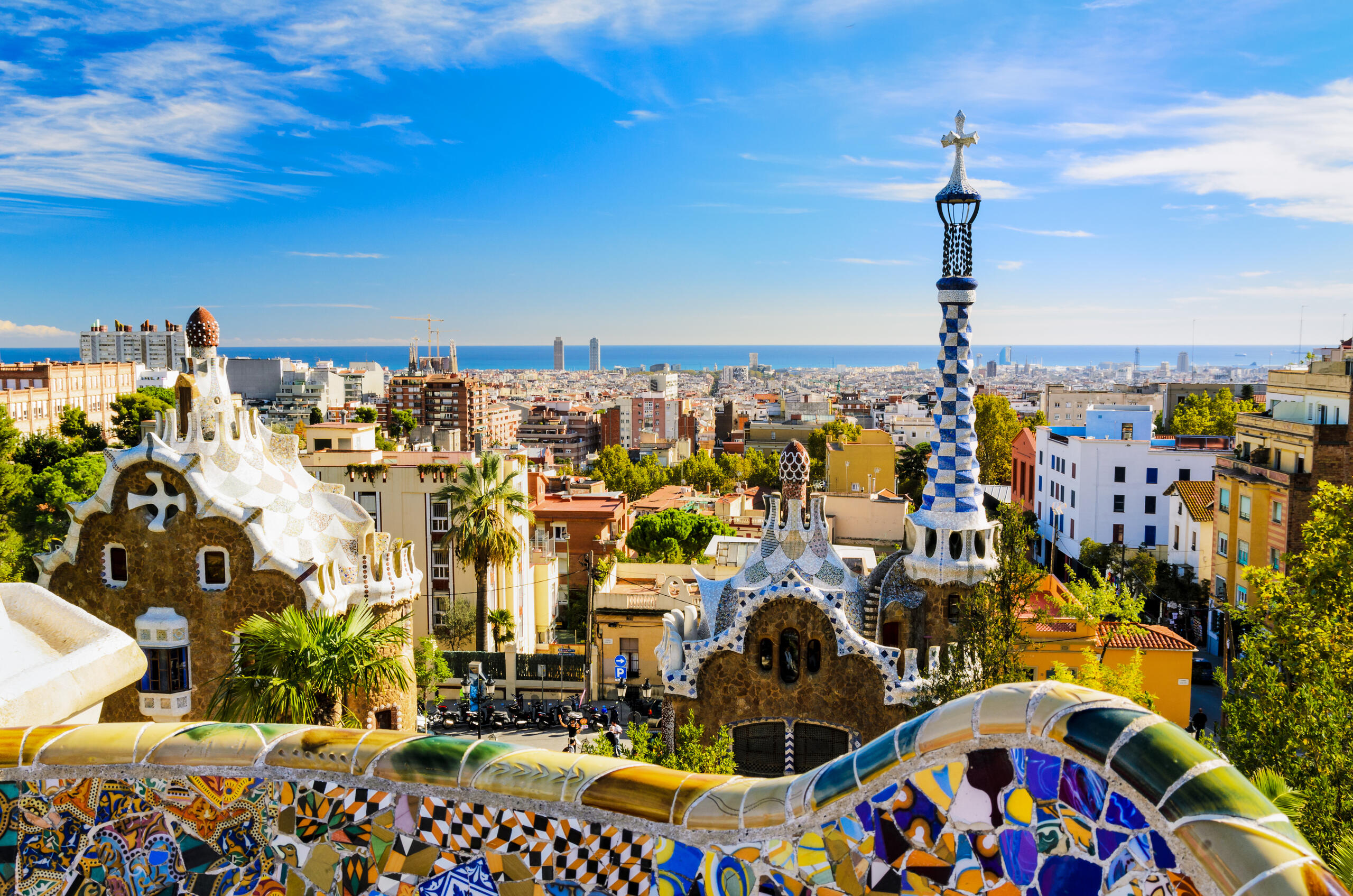 Panoramic city view of Barcelona, Spain, with the Sagrada Familia, colorful rooftops, and the Mediterranean Sea.