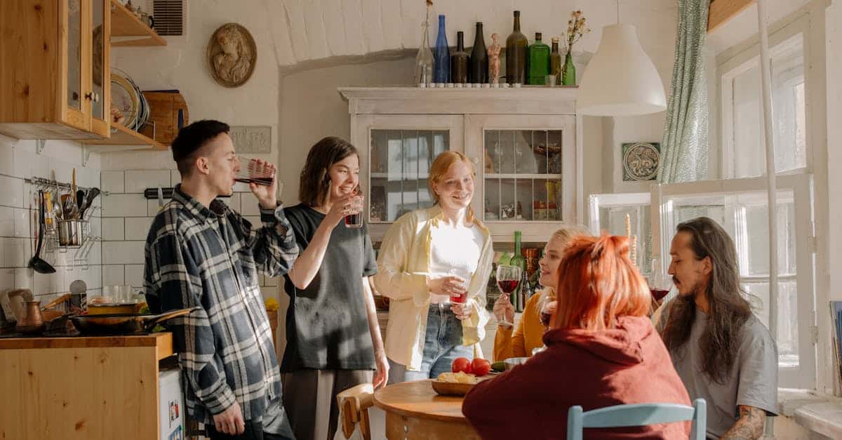 A group of friends laughing and enjoying drinks in a cozy kitchen, fostering a positive and considerate co-living environment.