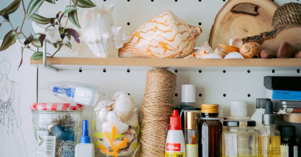 Organized shelves displaying crafting supplies, tools, and natural elements in a creative workspace, showcasing renter-friendly wall organization ideas.