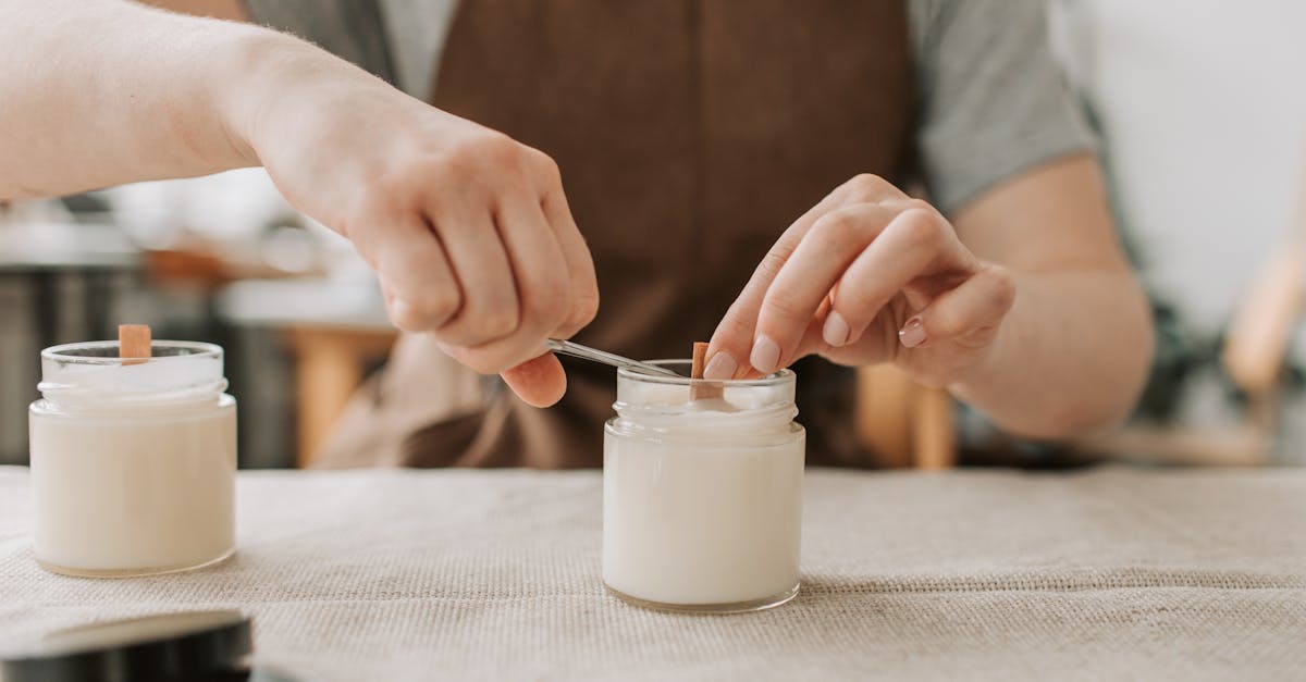 A person pouring melted wax into candle jars, creating custom-scented DIY candles for a cozy home ambiance.