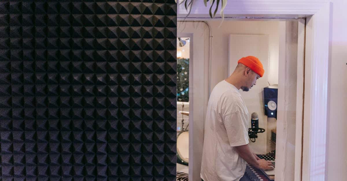 Side view of a man in a music studio with soundproof material, focused on a laptop, illustrating renter-friendly soundproofing solutions.