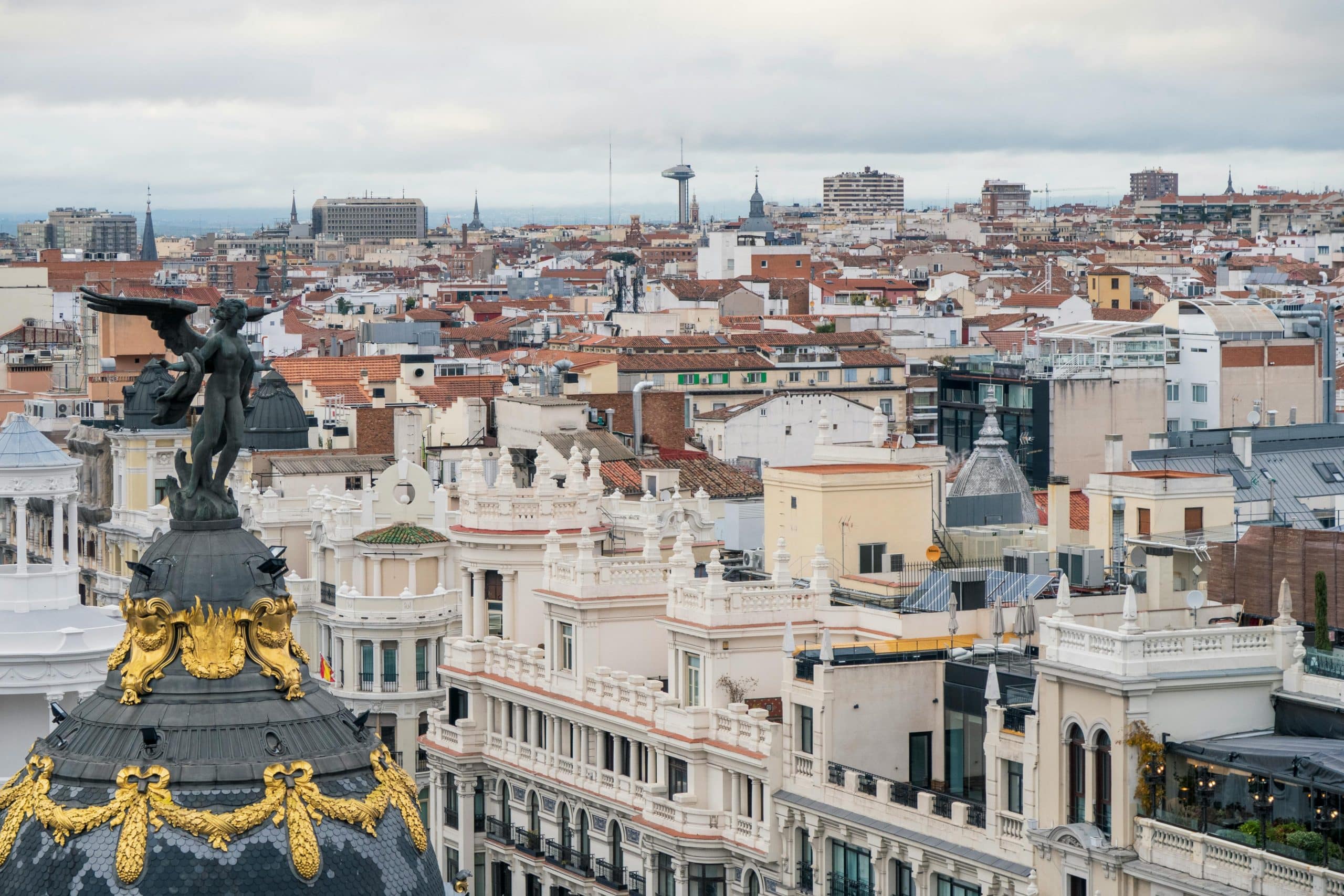 A captivating view of Madrid's iconic Metropolis Building amidst historic rooftops.