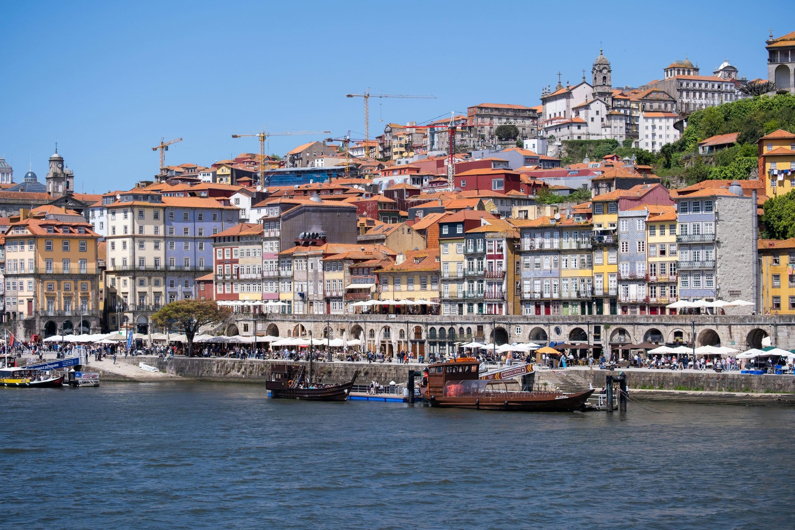 Colorful waterfront view of Ribeira District, Porto's historic charm under a bright sky.