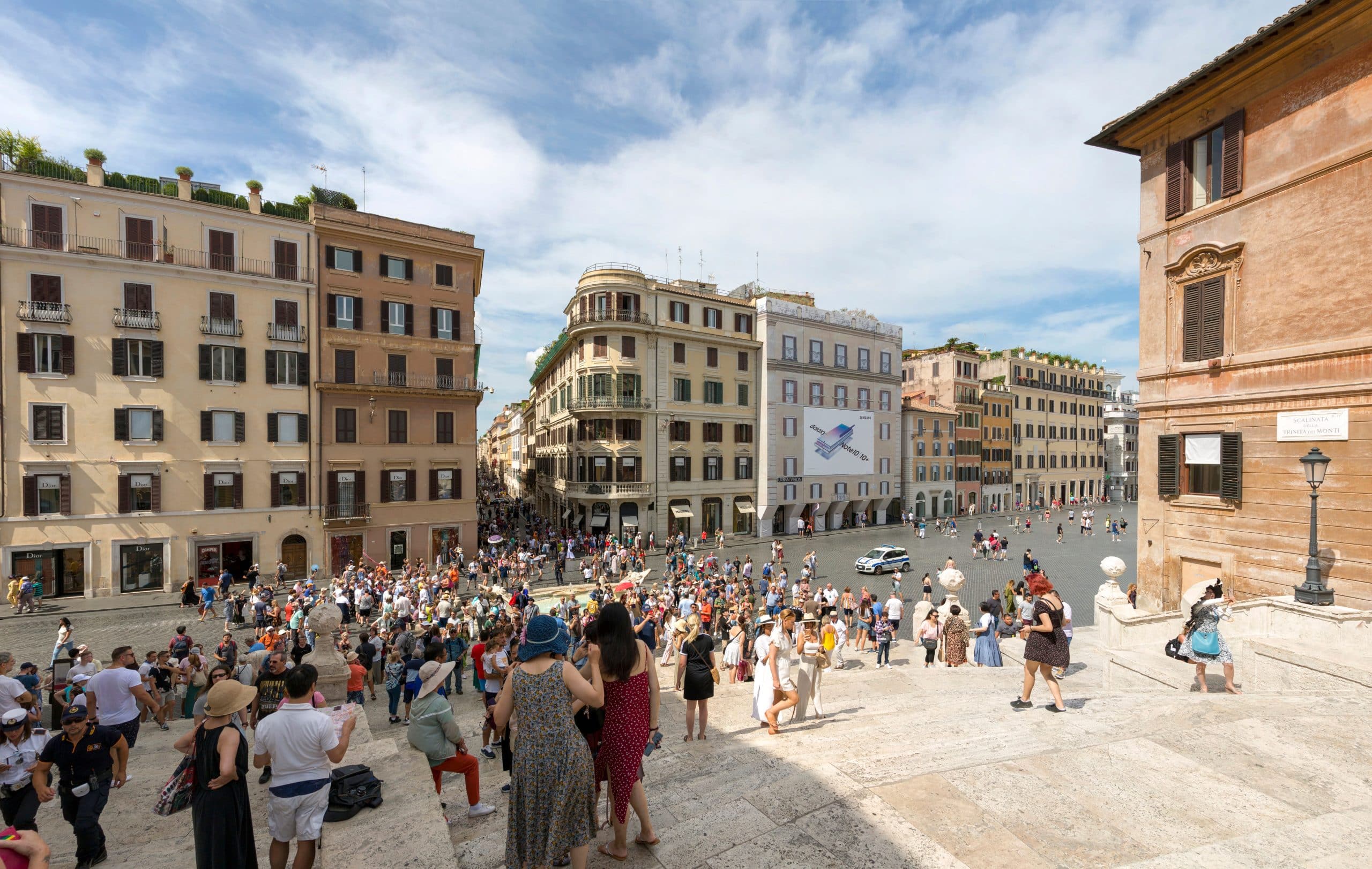 Bustling scene of tourists on the Spanish Steps in Rome under a sunny sky.