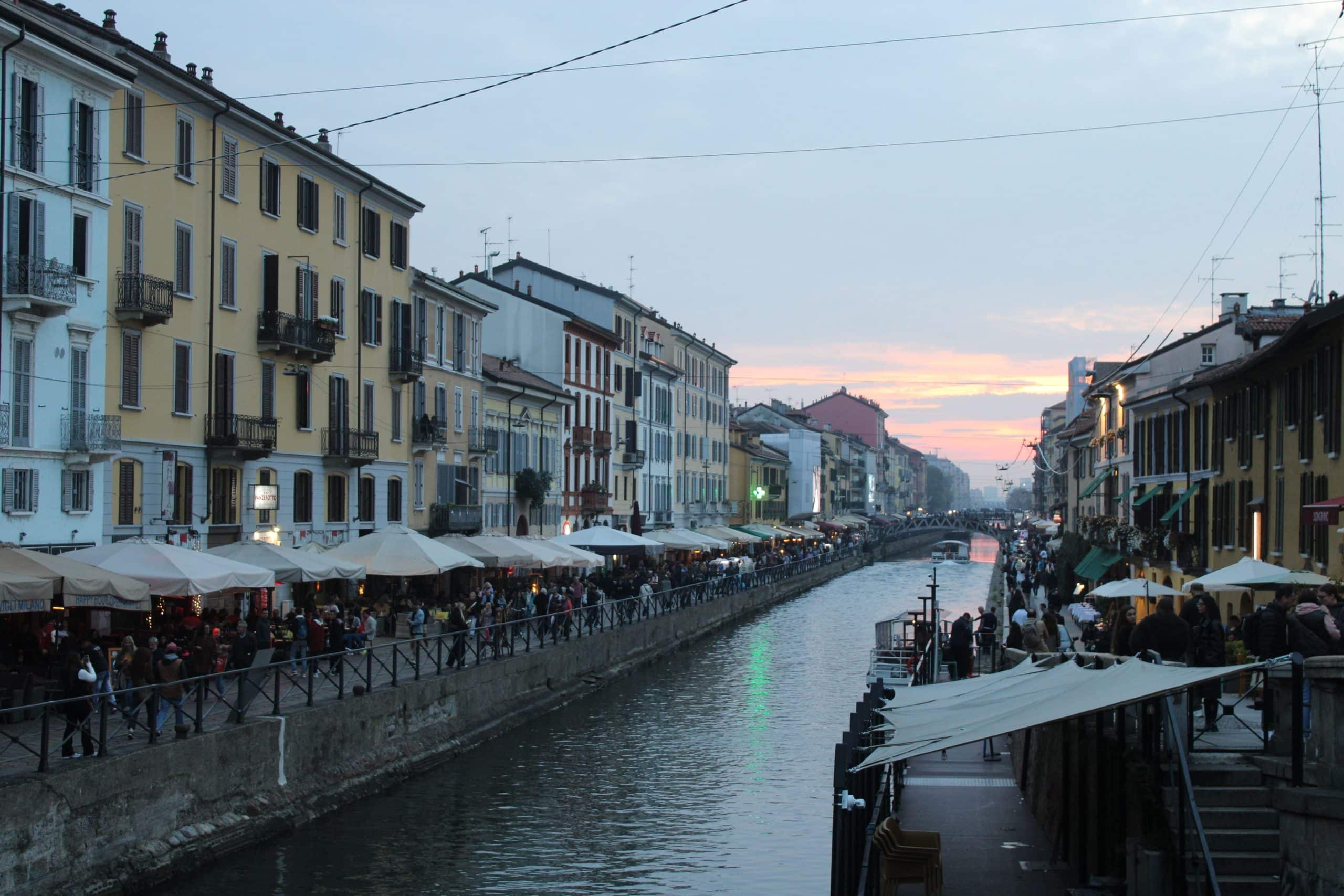 Scenic evening view of Naviglio Grande canal in Milan with vibrant street life.
