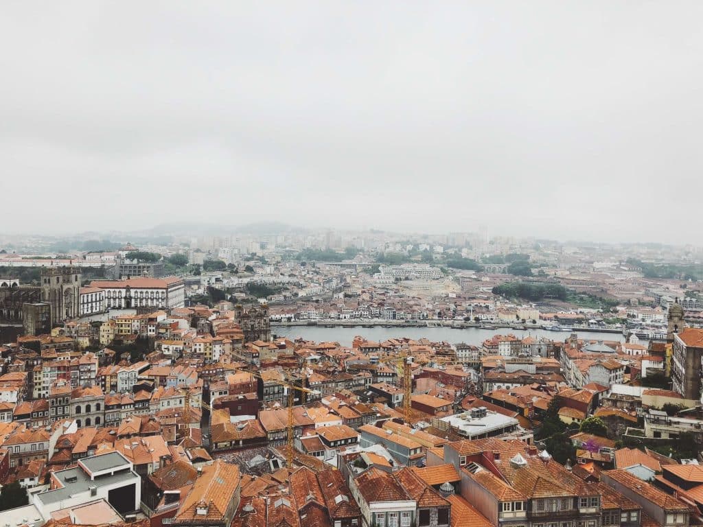 Aerial view capturing Porto's historic rooftops and Douro River under a misty sky.