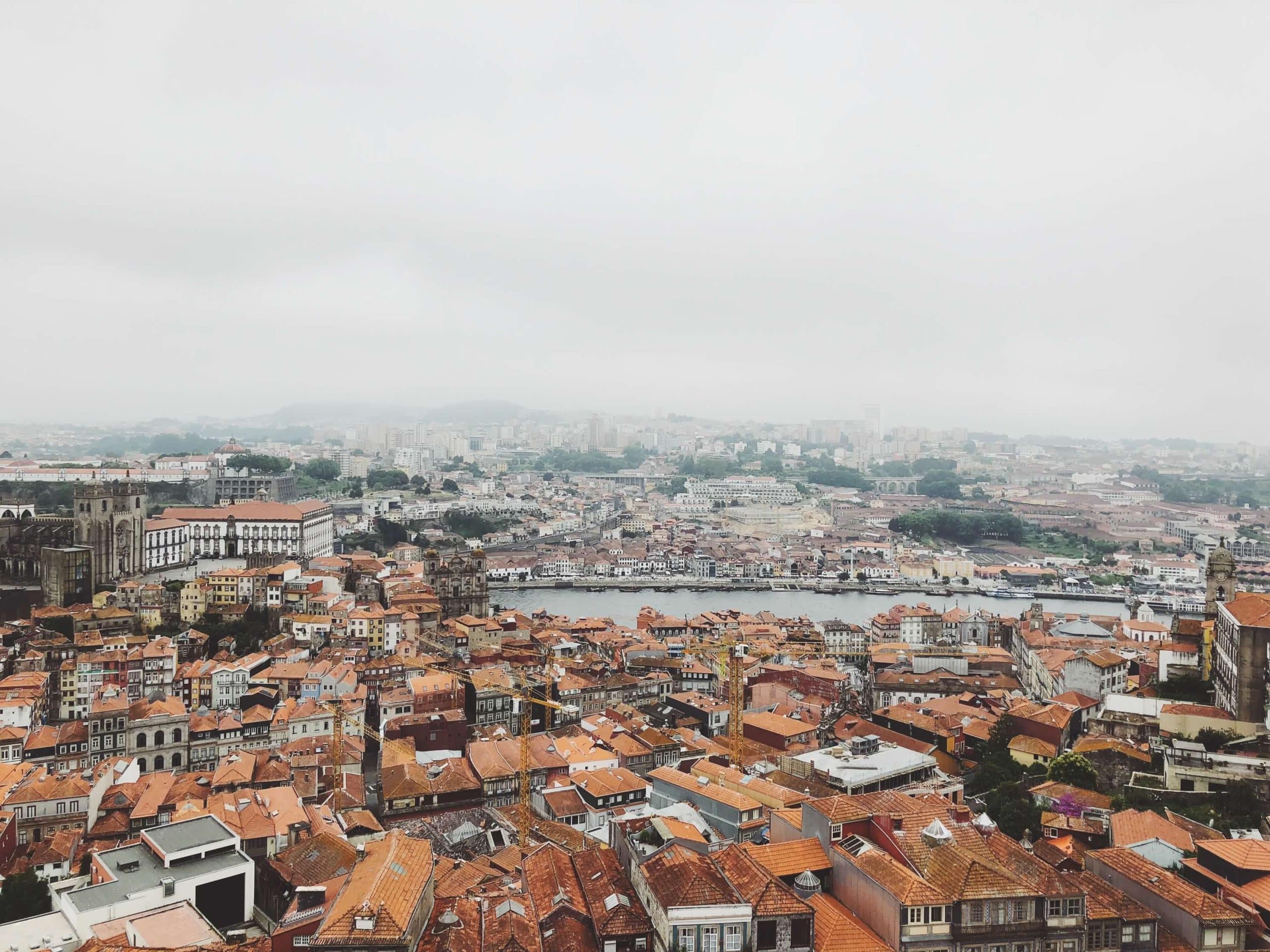 Aerial view capturing Porto's historic rooftops and Douro River under a misty sky.